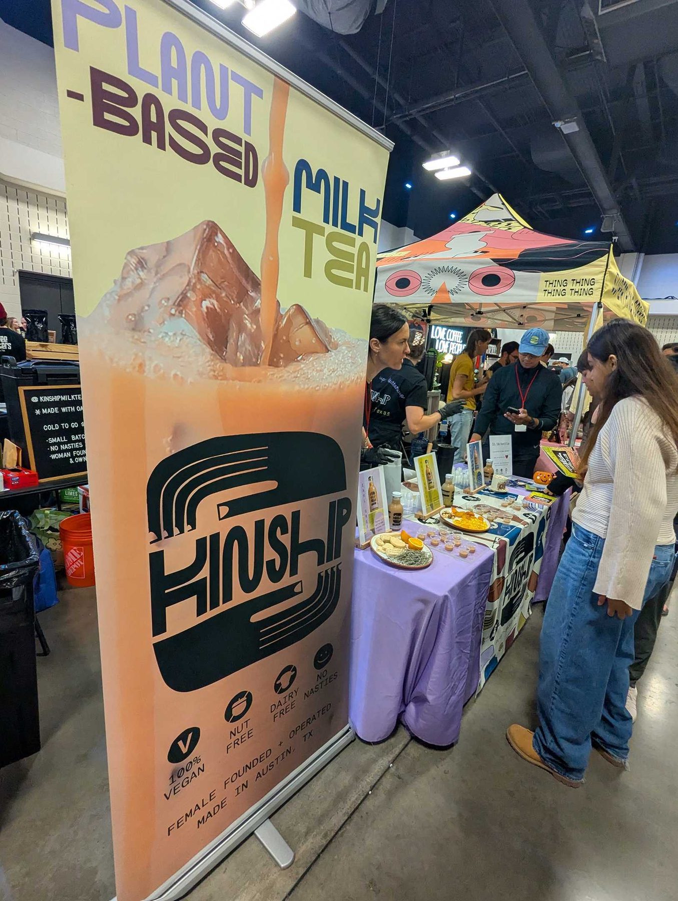 A festival vendor booth mid-event, banner raised and product laid out along the counter.