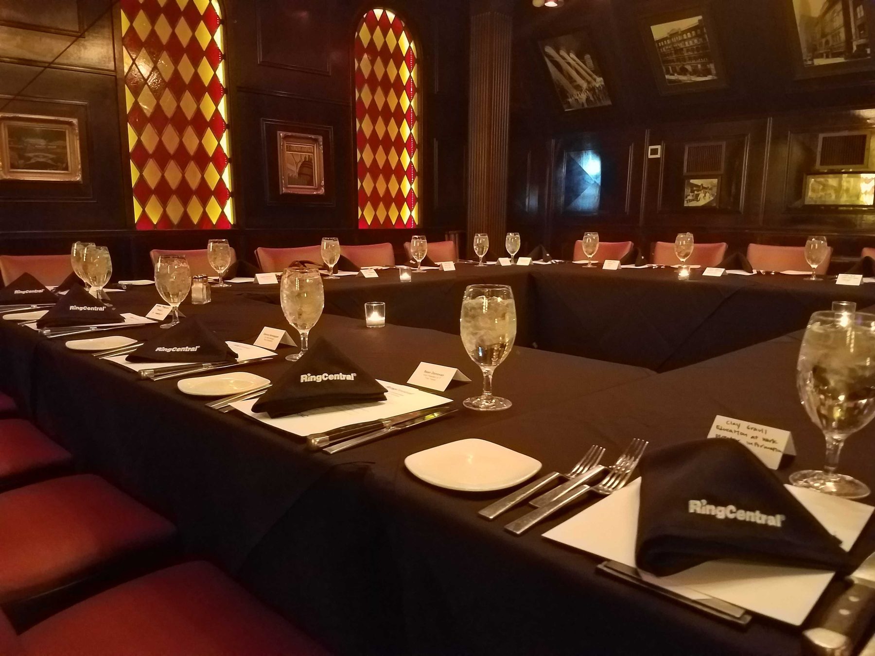 A long table laid for a private dinner in a dark paneled room, places set the length of it.