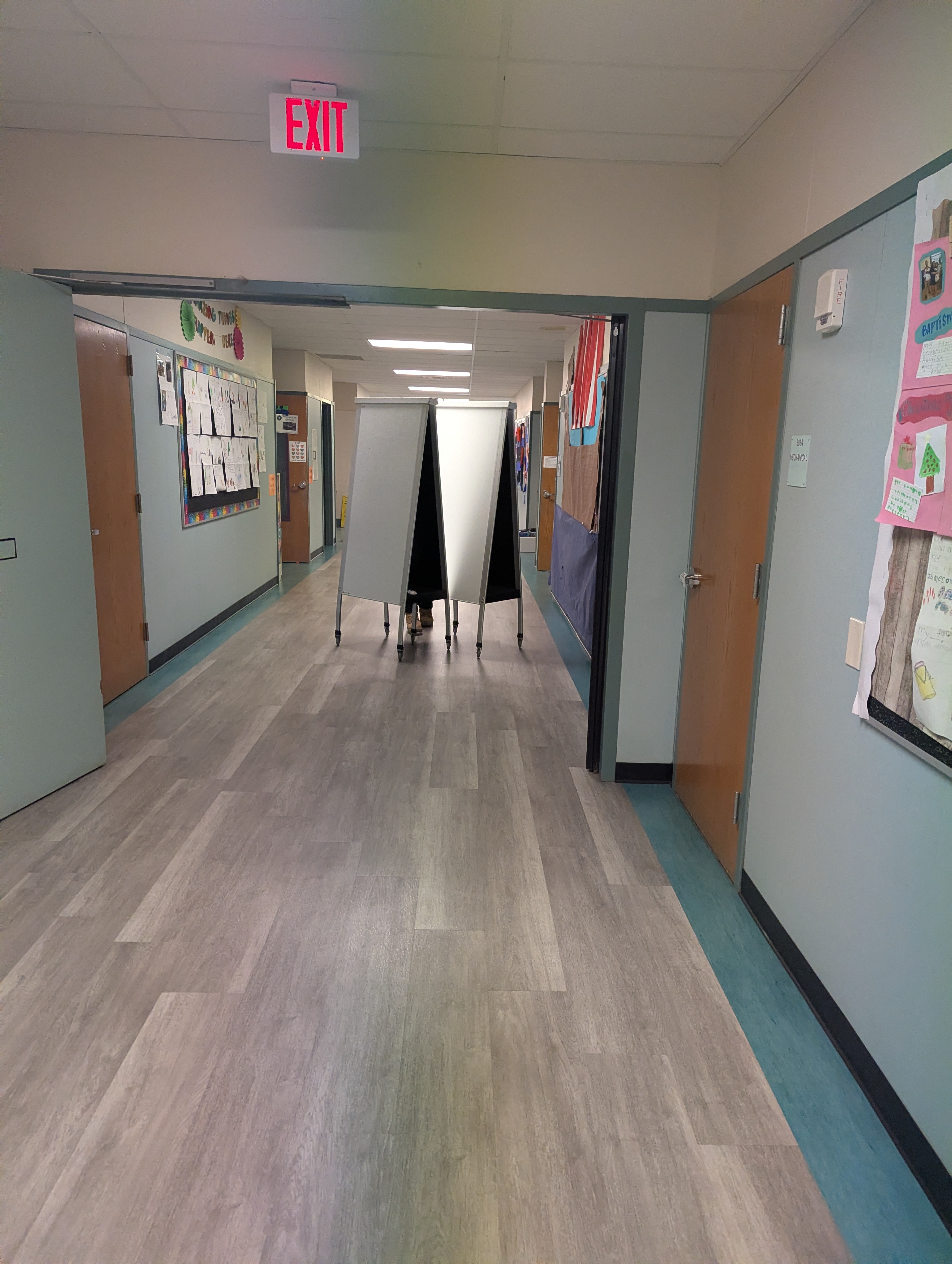 A classroom part way through a furniture turnover, old desks stacked on carts along one wall and a crew working at the back of the room.