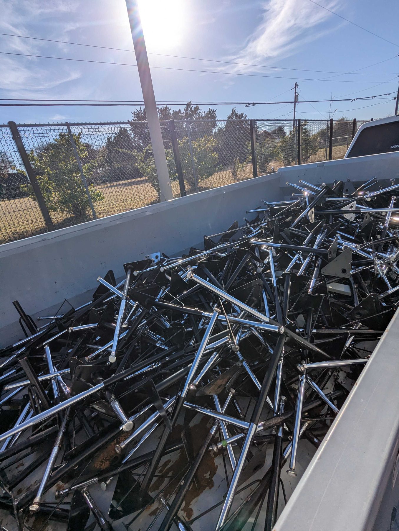 A large metal container piled high with dismantled table frames and legs.