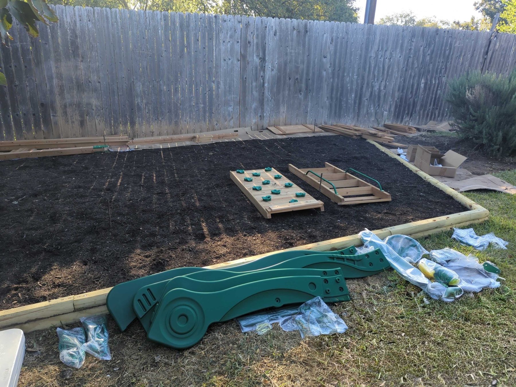 A yard prepared for a build: a level bed edged with timber, with components laid out on the ground ready to assemble.