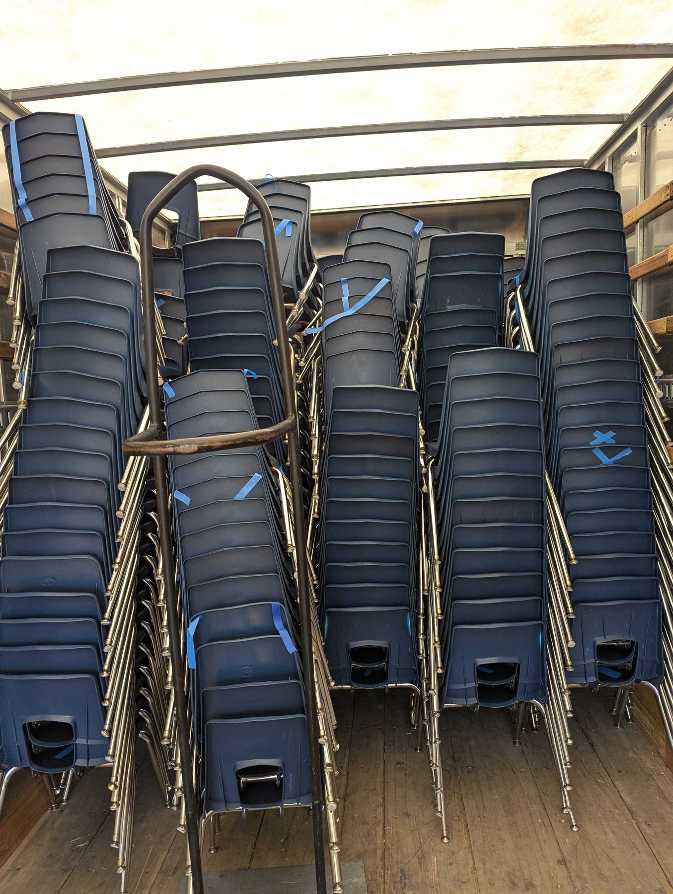 Stacked chairs and folded tables loaded into the back of a truck, ready to move.